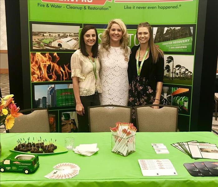 three girls in front of tradeshow booth 